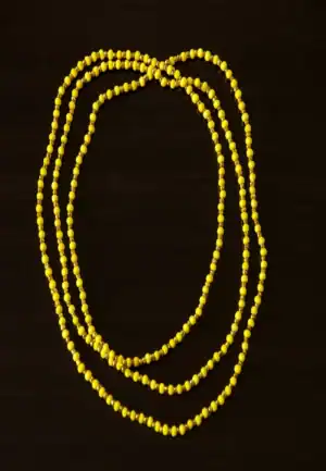 Perline gialle su sfondo nero, bijoux minimalista e colorato.
