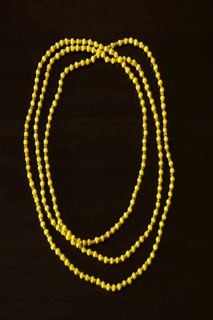 Perline gialle su sfondo nero, bijoux minimalista e colorato.